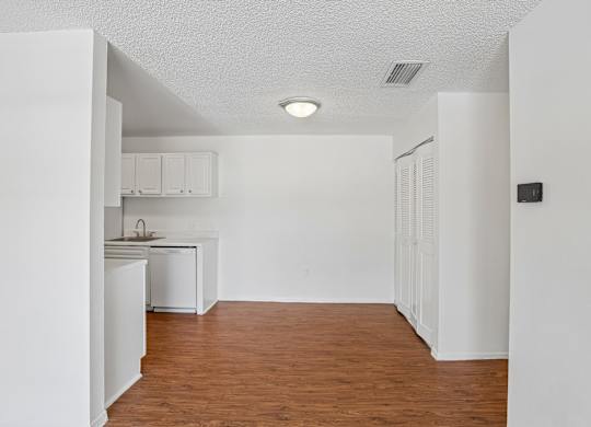 A kitchen with white cabinets and a wooden floor.