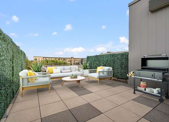A patio with a white couch, chairs, and a grill.