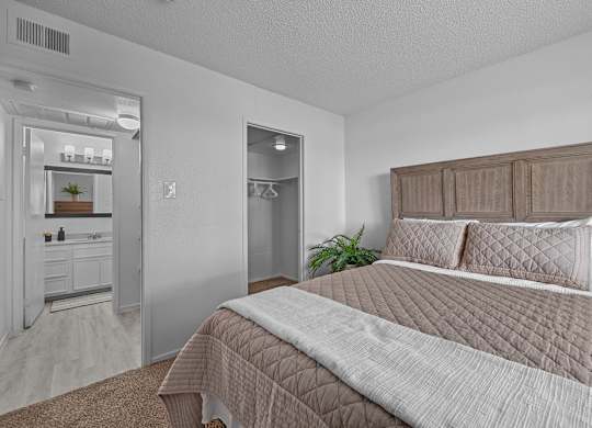 A bedroom with a large bed and a mirrored closet.