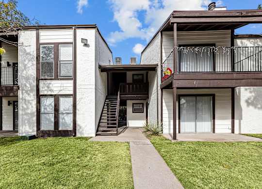 A white two-story house with a balcony on the upper floor.