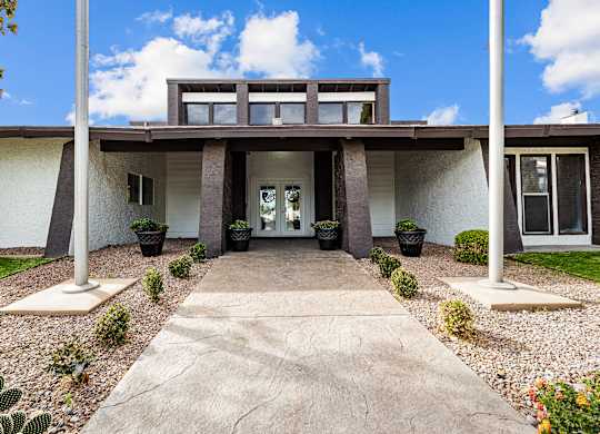 the front of a building with two pillars and a concrete walkway