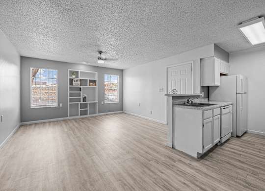 the living room and kitchen of an apartment with white appliances and wood floors