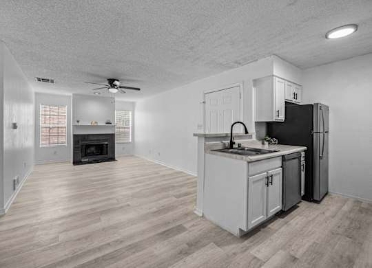 an empty living room with a kitchen with a stove and refrigerator