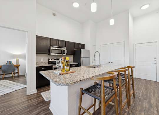 A kitchen with a granite countertop and bar stools.