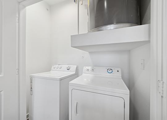 Two white front loading washing machines in a small laundry room.