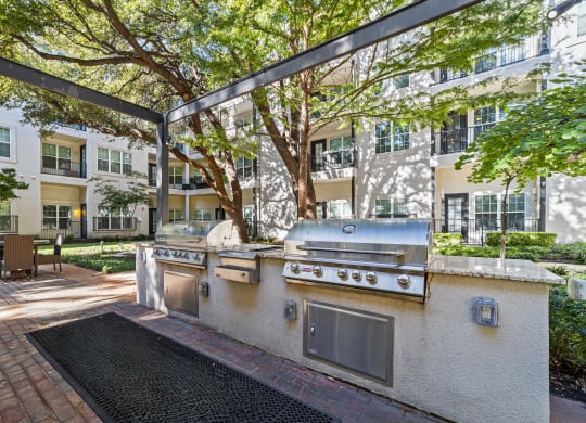 an outdoor kitchen with stainless steel appliances in front of an apartment building