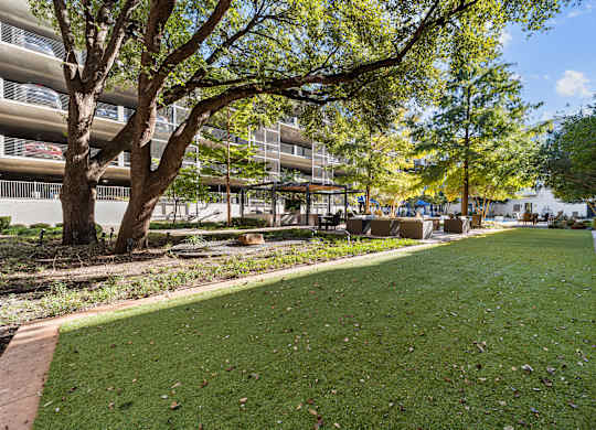 a park with grass and trees in front of a building