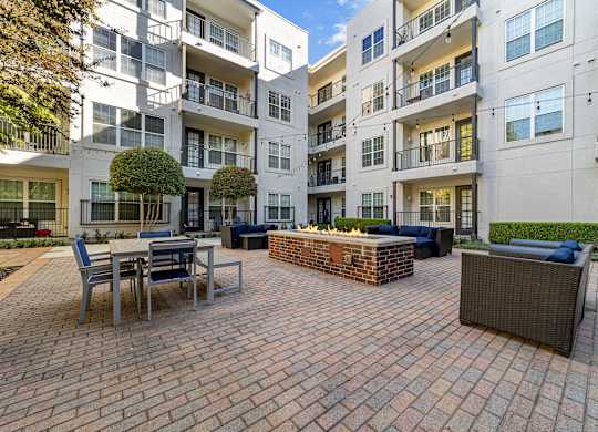 a brick patio with a fire pit in front of an apartment building