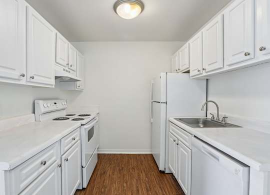 A white kitchen with wood floors and white appliances.