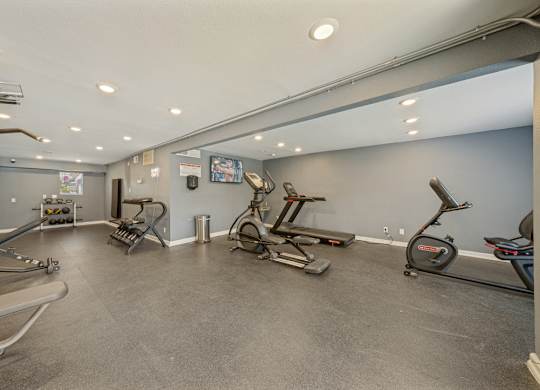 A spacious gym with treadmills, exercise bikes, and elliptical machines.
