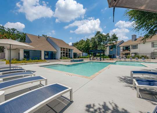 A sunny day at the pool with lounge chairs and a clear blue sky.