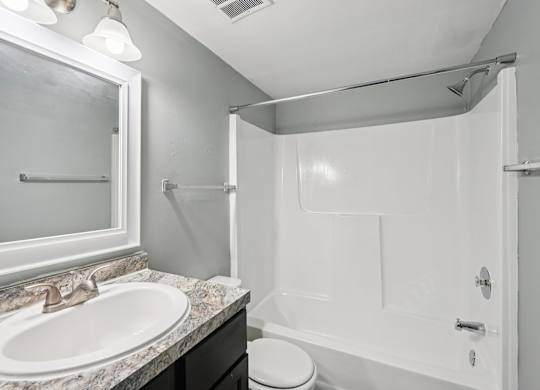 A white bathroom with a sink, toilet, and shower.