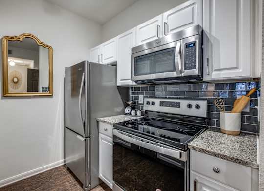 an updated kitchen with stainless steel appliances and white cabinets