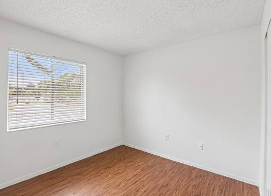 A room with a window and wooden flooring.
