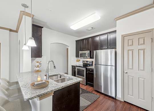 A kitchen with a sink, refrigerator, and oven.
