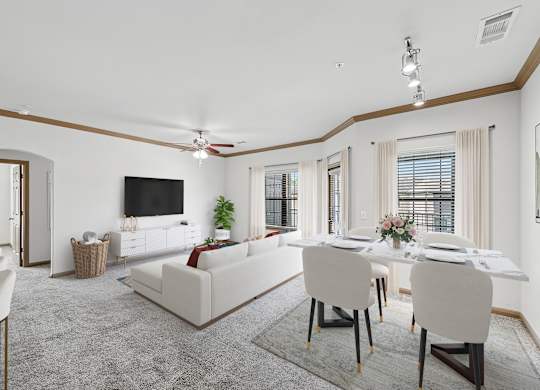 A living room with a white couch and a dining table set up.