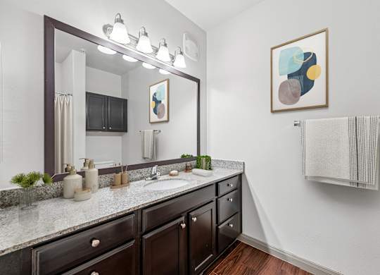 A bathroom with a large mirror, a sink, and a towel rack.