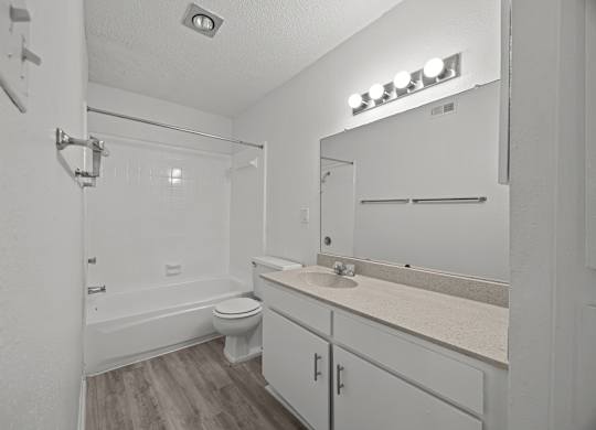 A white bathroom with a toilet, sink, and mirror.