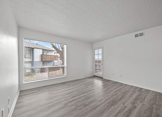 Empty room with wooden flooring and a window showing an outdoor view.