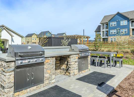A stone outdoor kitchen with a grill and sink.
