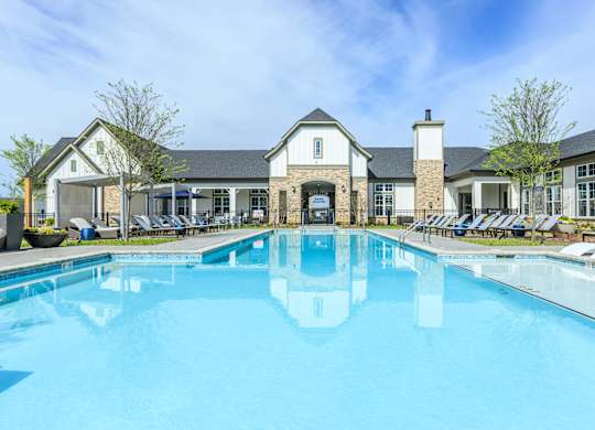 A large swimming pool in front of a building with a white facade.