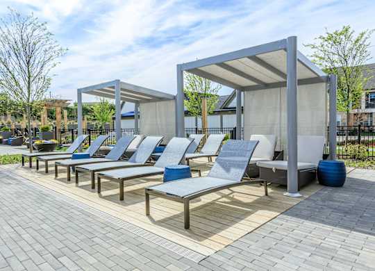 A row of blue and white lounge chairs are arranged on a patio.