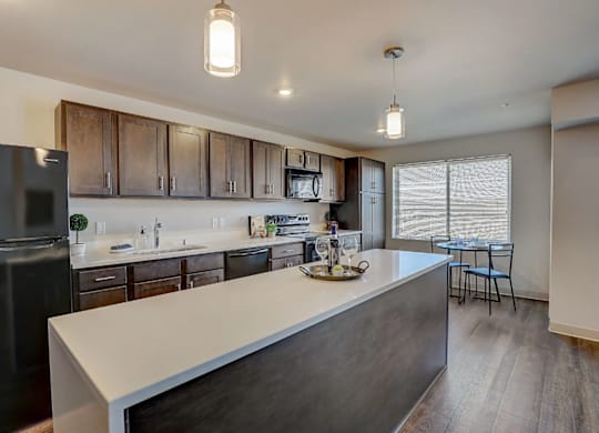 A modern kitchen with a black fridge and wooden cabinets.