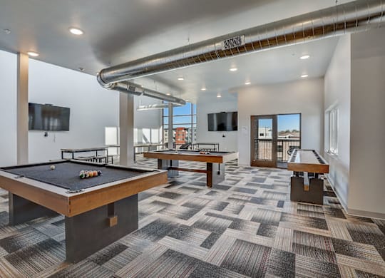 A room with a pool table and a tv mounted on the wall.