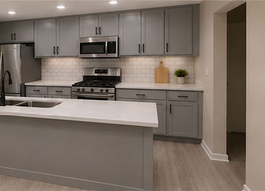 A kitchen with a white countertop and grey cabinets.