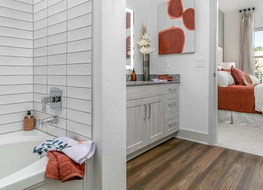 A bathroom with a white tub and a wooden floor.