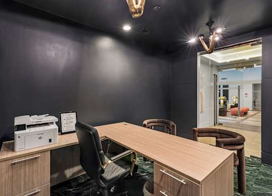 A conference room with a large table, chairs, and a printer on a desk.