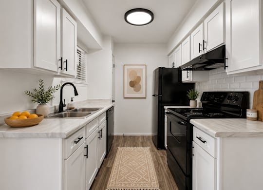 A kitchen with black appliances and white cabinets.