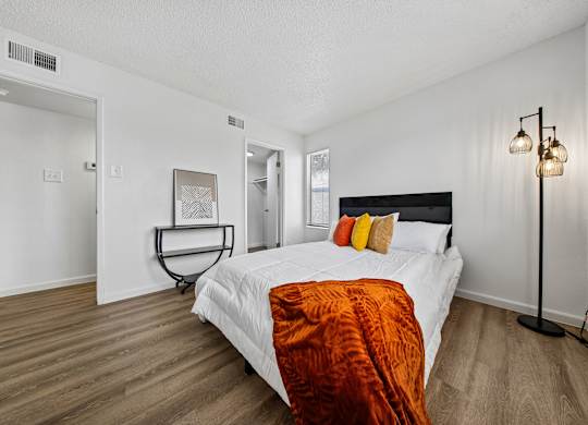 A bedroom with a bed, a lamp, and a chair.