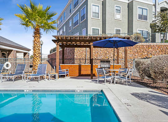 A pool with a blue umbrella and a wooden fence.
