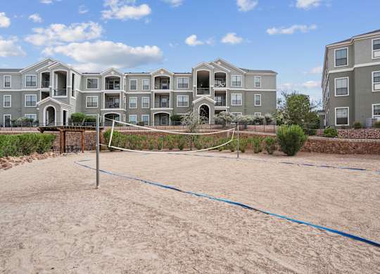 A sand volleyball court in front of apartment buildings.