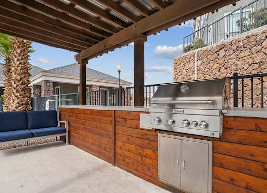 A wooden outdoor kitchen with a grill and a bench.