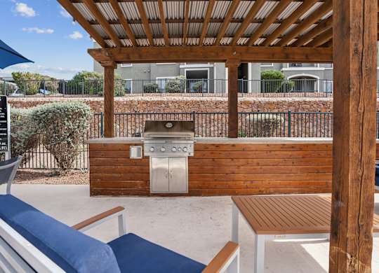 A wooden pergola with a grill and seating area.