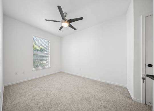 A room with a ceiling fan and a window with blinds.