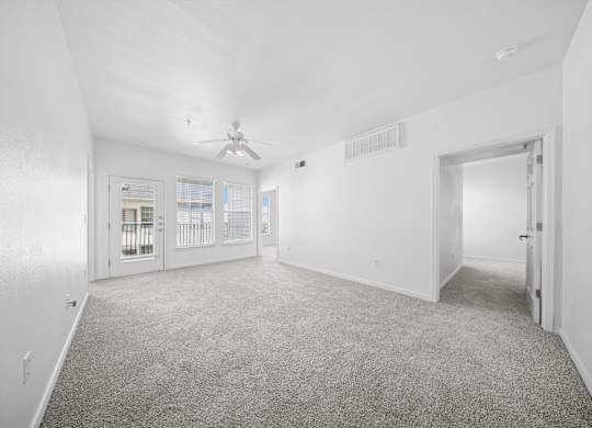 A spacious room with a carpeted floor and a ceiling fan.