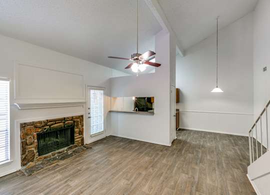 an empty living room with a fireplace and a ceiling fan