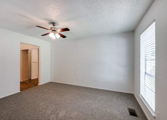 the living room of an empty house with a ceiling fan