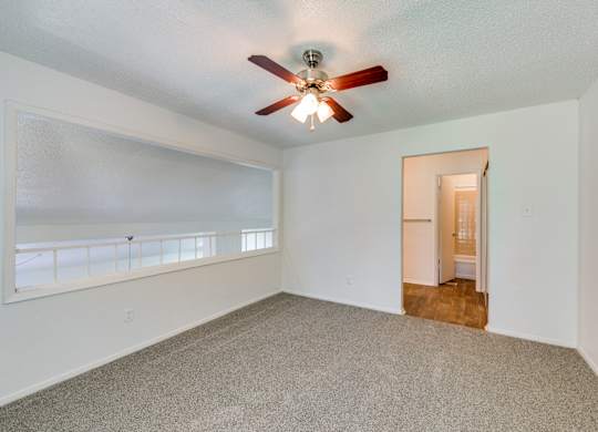an empty living room with a ceiling fan
