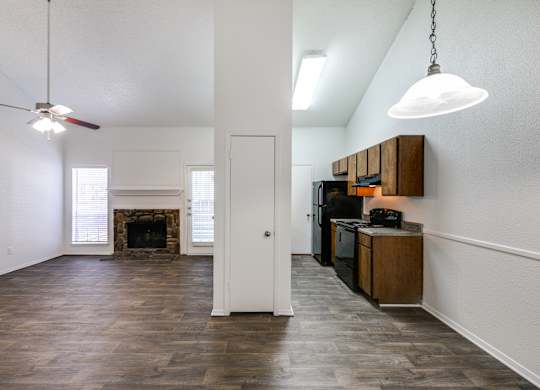 an empty living room with a fireplace and a kitchen