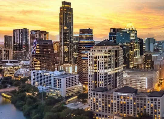 A city skyline at sunset with a river running through it.