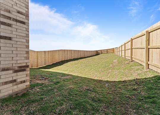 a backyard with a wooden fence and grass