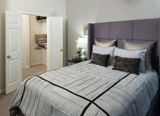 A bed with a striped comforter and two pillows with a black design on them.