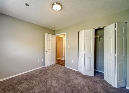 a empty room with closet doors and a door to a hallway