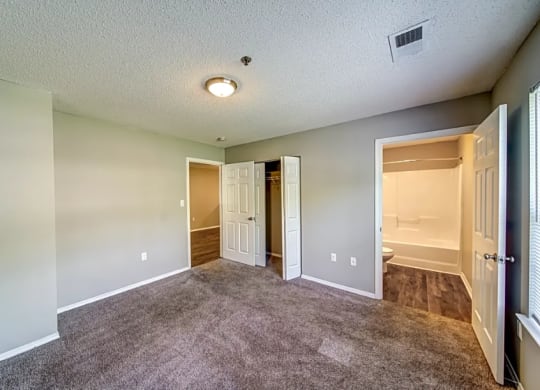 an empty living room with a door to a bathroom and a closet