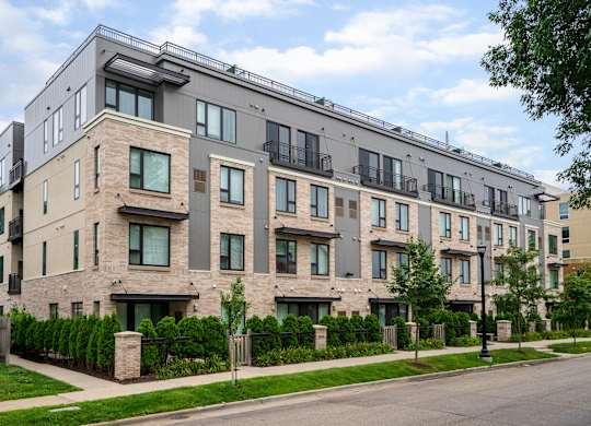 A modern apartment building with balconies and a mix of stone and siding exteriors.