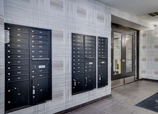 A hallway with a wall of mailboxes and a door at the end.